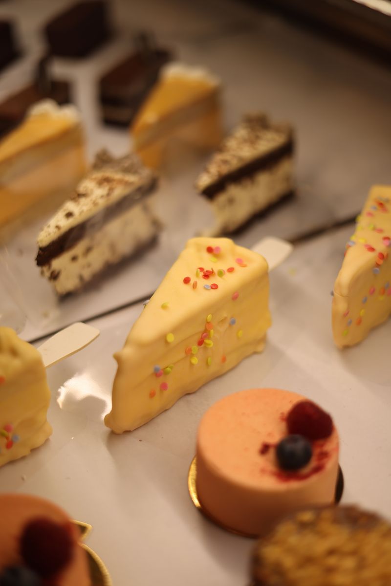 Illustrative selection of cake slices and small frosted cakes on display.