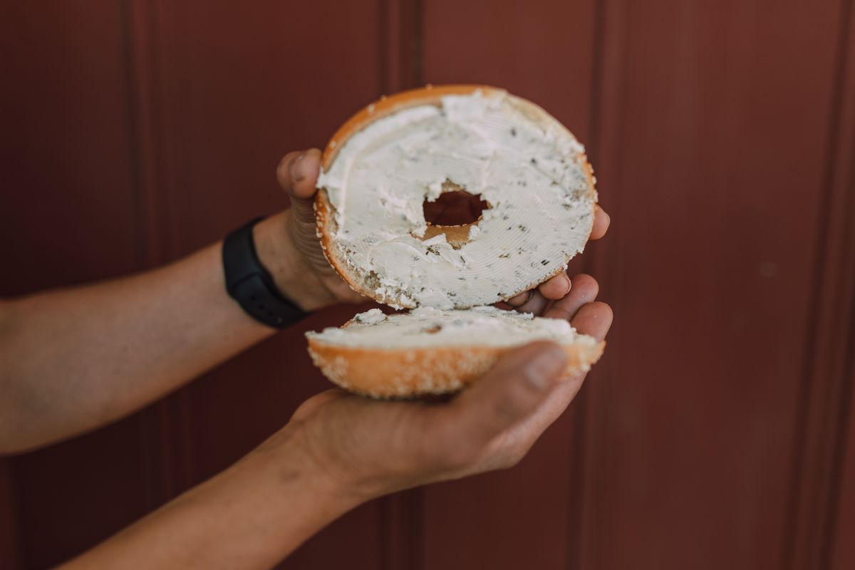 Illustrative photo of a sliced bagel spread with cream cheese.