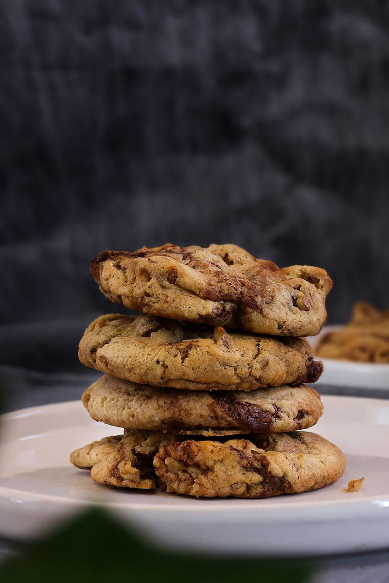 Illustrative stack of golden chocolate chip cookies on a white plate.