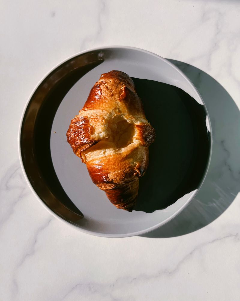 Illustrative golden croissant on a simple gray plate.