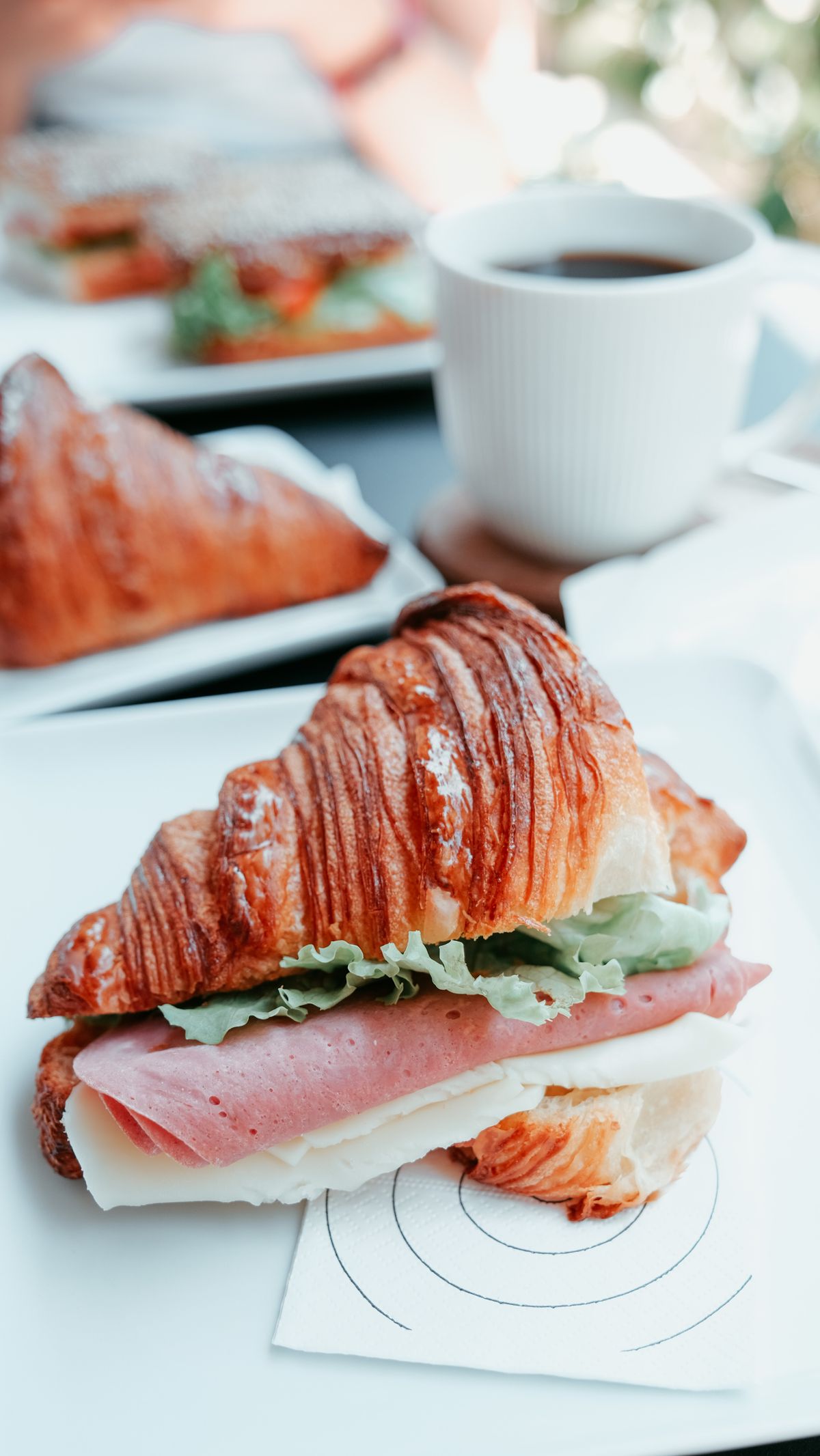 Illustrative photo of a ham and cheese croissant with lettuce.