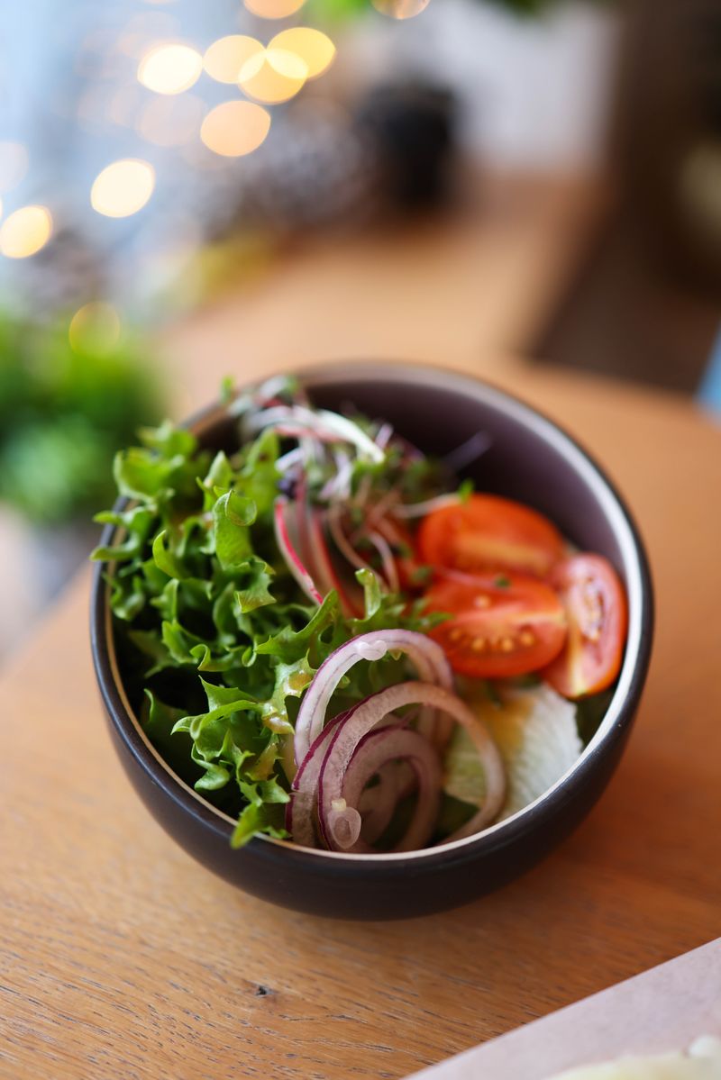 Illustrative mixed lettuce salad with red onion rings and tomato slices.