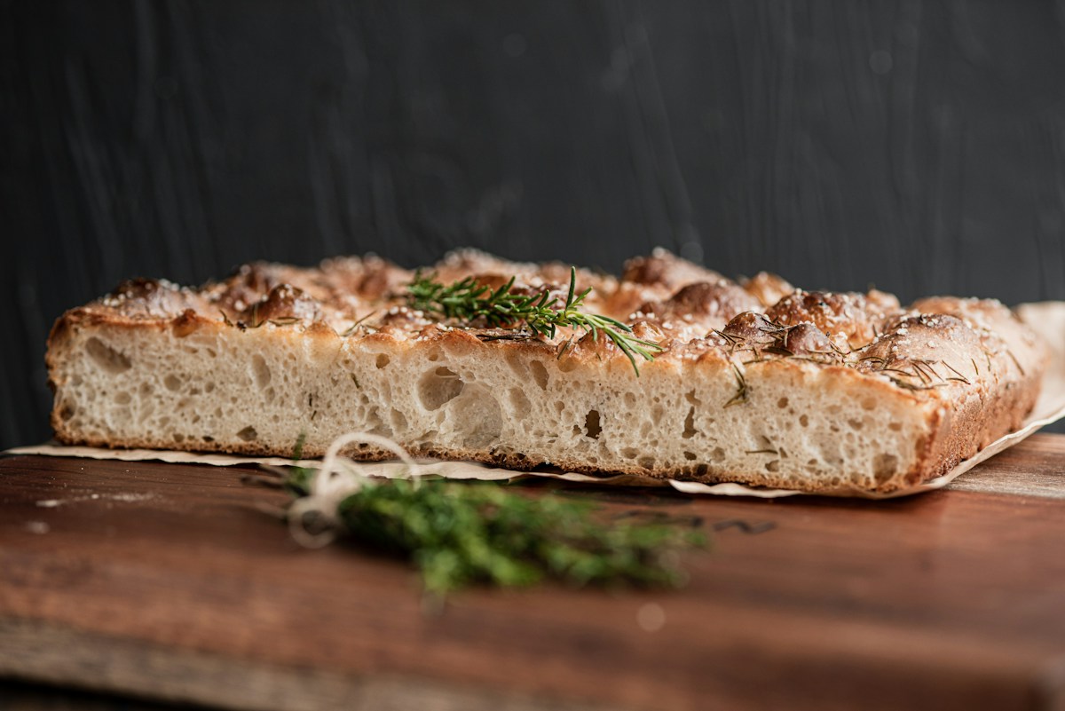 Rosemary focaccia bread on a wooden board; the finished salmon sandwich is not pictured.