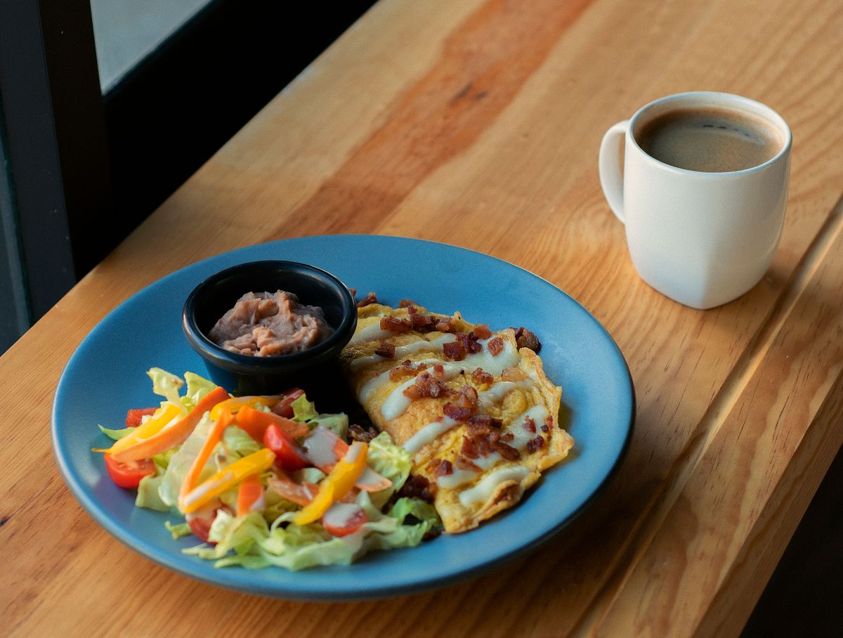 Illustrative photo of a folded omelette topped with bacon, served with vegetables.