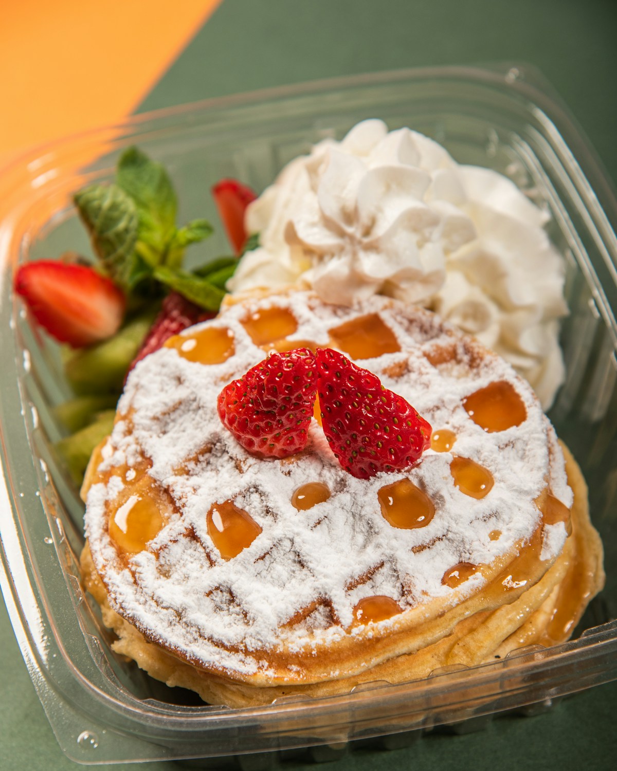 Illustrative photo of a waffle with strawberries, whipped cream and syrup.