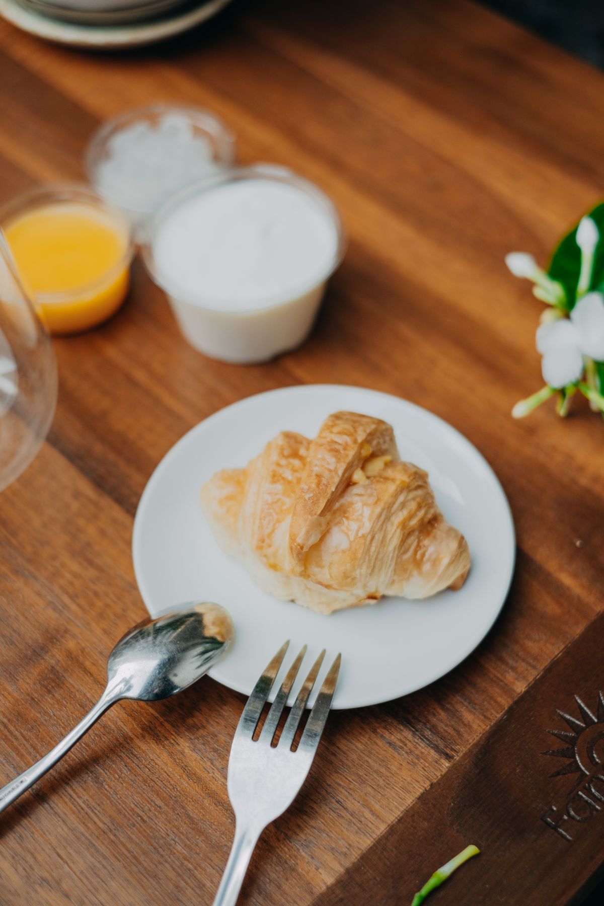 Plain croissant on a white plate; the finished turkey and cheese sandwich is not pictured.