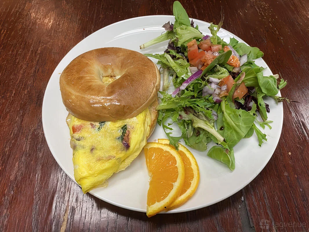 An egg-filled bagel with a side salad and orange slices at Zed’s Cafe.